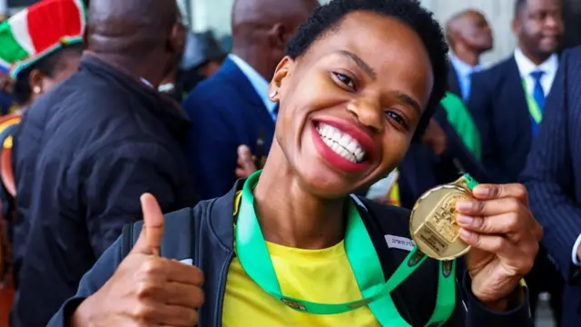 Hildah Magaia, a football player for the South African women's team, shows off her medal during their arrival, after winning their first Women's Africa Cup of Nations title in Morocco, at OR Tambo International Airport in Johannesburg, South Africa, July 26, 2022.