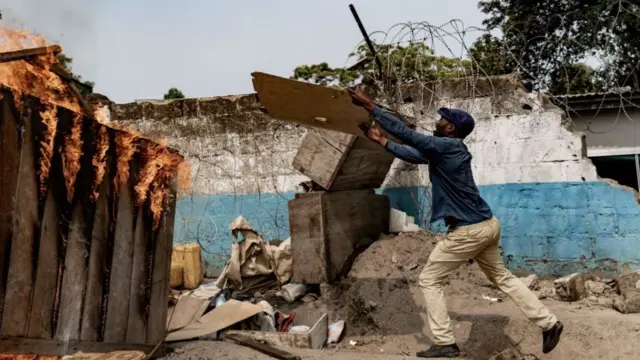 Protesters throw items into a burning barricade at the scene of a looted warehouse belonging