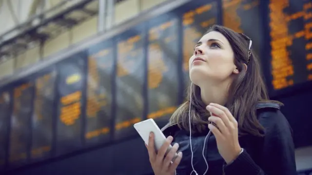 A woman holds a mobile phone at a railway station