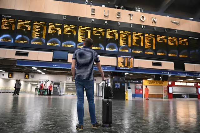 Man looking at departure boards at Euston station, London