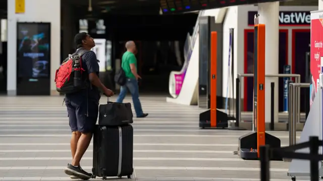 A passenger looks at message boards at Birmingham New Street Station