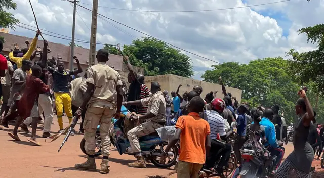 A crowd gathers around a man (not seen) suspected of taking part in thwarted "terrorist" attack after being beaten by a crowd, in front of the military base in Kati, Mali, on July 22, 2022.