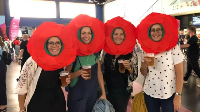 Four women with rose hats on