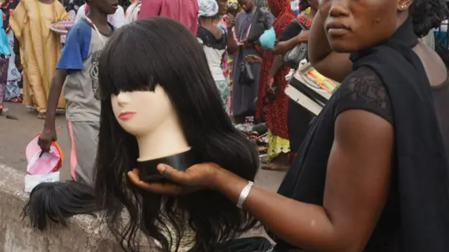 Woman carrying a mannequin wearing a wig