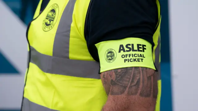 A man wearing an Aslef hi-vis vest on the picket line in Leeds