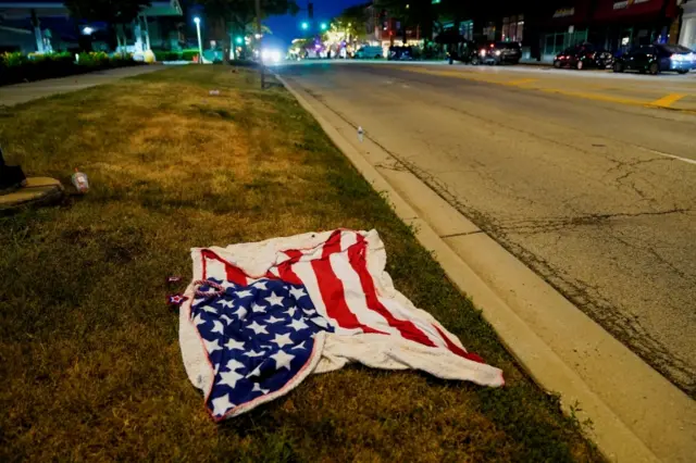 A blanket bearing the US flag is seen abandoned along the parade route after a mass shooting at a Fourth of July parade in Highland Park