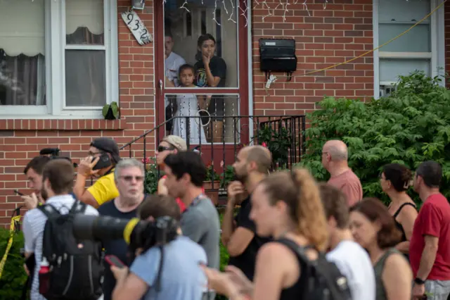 A family looks outside of their front door near the home of the mother of the man detained in the mass shooting at an Independence Day parade in Highland Park