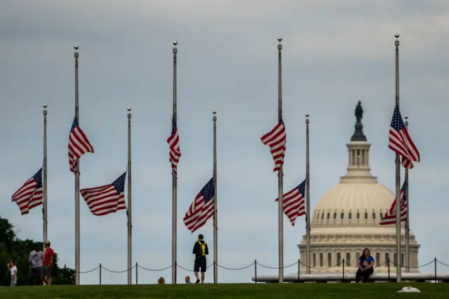 American flags are seen at half-mast surrounding the Washington Monument as people enjoy the weather on the National Mall on Wednesday, May 25, 2022 in Washington, DC