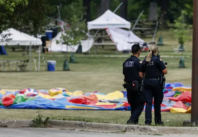 Police stand guard along the parade route in Highland Park, 4 July 2022