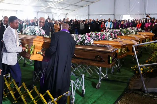 Mourners place empty coffins ahead of a mass funeral for victims of an east coast tavern