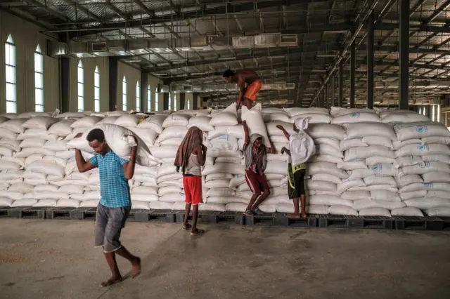 Workers carry sacks of grain in a warehouse of the World Food Programme (WFP) in the city of Abala, Ethiopia, on June 9, 2022