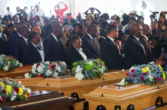 South African President Cyril Ramaphosa walks past empty coffins as he arrives ahead of the mass funeral