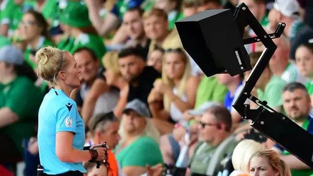 A photo of a referee checking a VAR monitor
