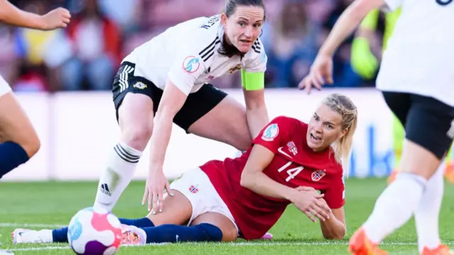 A photo of Ada Hegerberg being challenged on the pitch