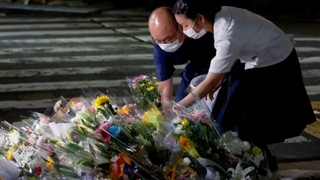 People lay flowers at the site where late former Japanese Prime Minister Shinzo Abe was shot while campaigning for a parliamentary election, near Yamato-Saidaiji station in Nara