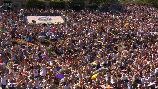 Crowds wave on the hill at Wimbledon