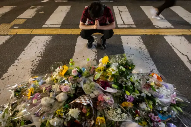 A man prays at a site outside of Yamato-Saidaiji Station where Japan’s former PM Shinzo Abe was shot and killed