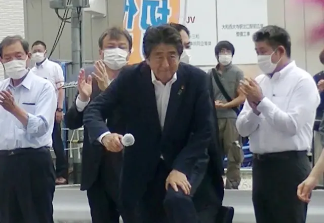 Former Japanese Prime Minister Shinzo Abe (C) steps up to podium to speak to voters in support of his party"s candidate during an Upper House election campaign outside Yamato-Saidaiji Station of Kintetsu Railway in Nara, western Japan