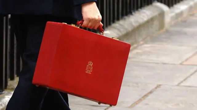 Unidentified person carrying a red budget briefcase