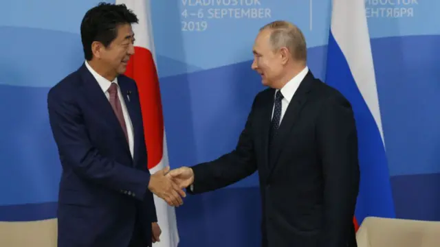 Russian President Vladimir Putin (R) greets then-Japanese PM Shinzo Abe during their bilateral meeting at the Russky Island on 5 September 2019 in Vladivostok, Russia