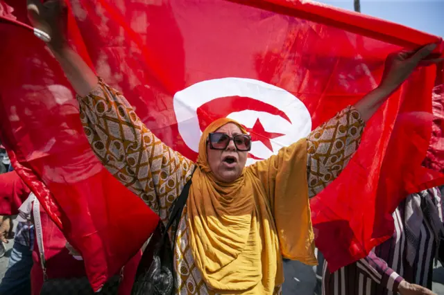 A woman waves the national flag at a protest against proposed constitutional changes