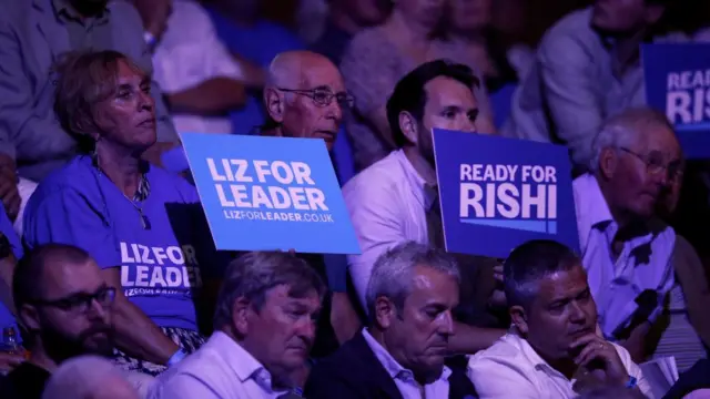 Supporters of Rishi Sunak and Liz Truss hold up signs supporting their chosen candidate at a hustings event in Exeter