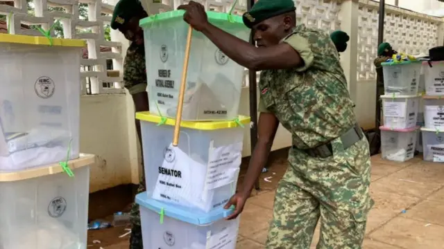 Officers carrying boxes of votes at Pwani University tallying centre