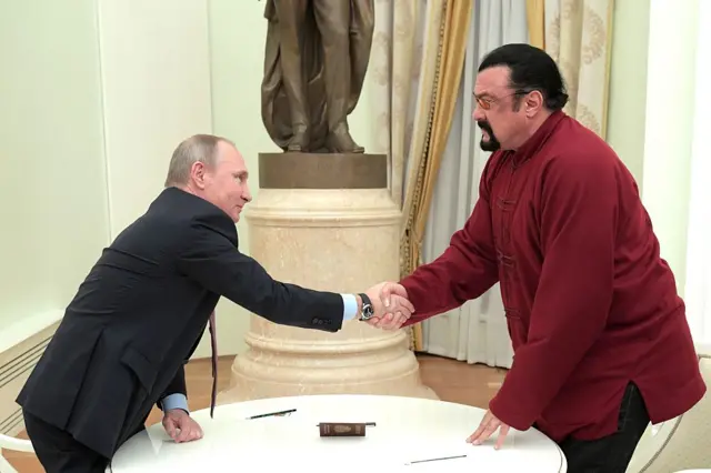 Russian President Vladimir Putin shakes hands with US action hero actor Steven Seagal after presenting a Russian passport to him during a meeting at the Kremlin in Moscow on 25 November 2016