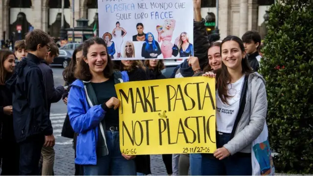 Climate activists holding a "make pasta not plastic" sign