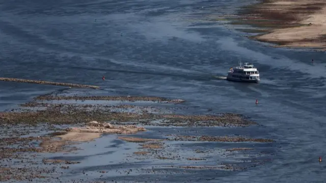 A tourist vessel cruises past the partially dried riverbed of the Rhine river in Bingen, Germany, August 9, 2022