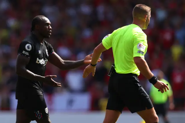 Michail Antonio of West Ham United interacts with Match referee Robert Jones