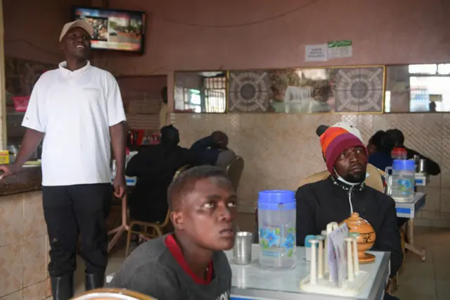 Residents watch television as they wait for the results of Kenya's national election in Eldoret on August 15, 2022.