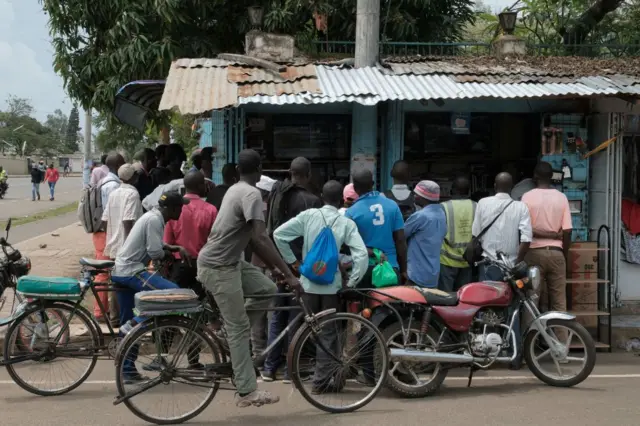 Residents watch television at an electronics shop as they wait for the results of Kenya's general election in Kisumu on August 15, 2022.