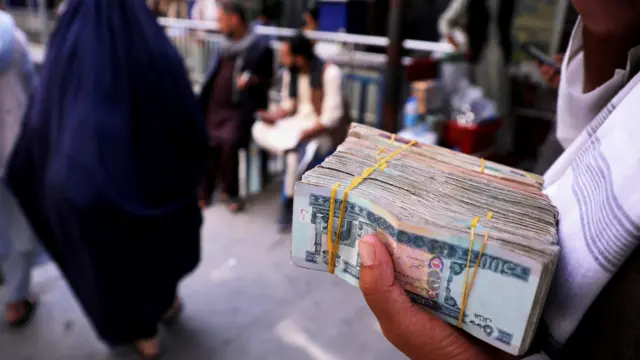 Person holds a bundle of Afghan banknotes at a money exchange in Kabul