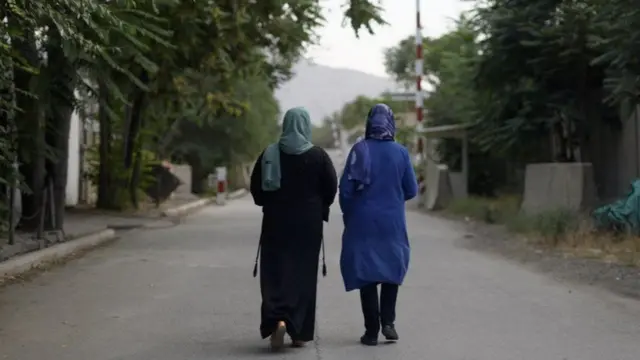 Two women walk down a road in Afghanistan