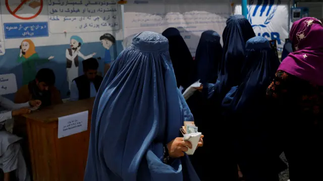 An Afghan woman receives a cash handout at a distribution centre for displaced people