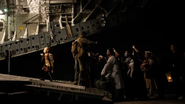 Evacuees from Afghanistan board a military aircraft during an evacuation from Kabul, on August 19, 2021