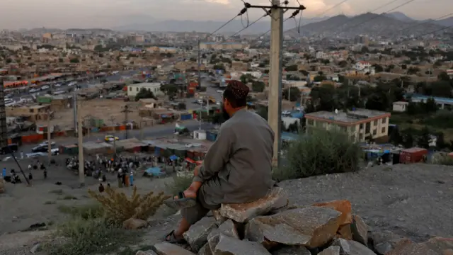 An Afghan man sits on a hilltop overlooking in Kabul