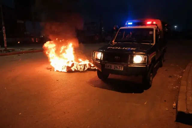 A Kenyan Police vehicle drives past burning debris laying in the road after supporters of Azimio la Umoja (One Kenya Coalition) presidential candidate Raila Odinga protested the results of Kenya's general election in Kisumu.