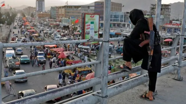 A Taliban fighter stands guard on a bridge in Kabul