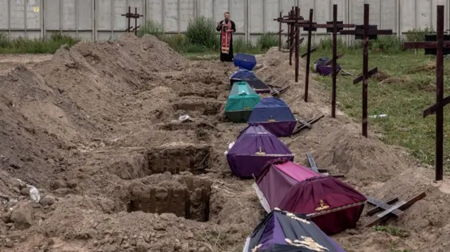 A priest blesses the remains of unidentified people killed in Bucha at the time of the Russian occupation at the start of the conflict.