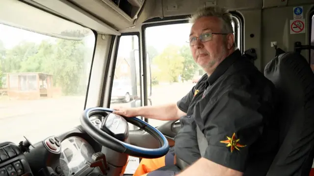 Shaun Coole poses for a photo at the steering wheel of a vehicle