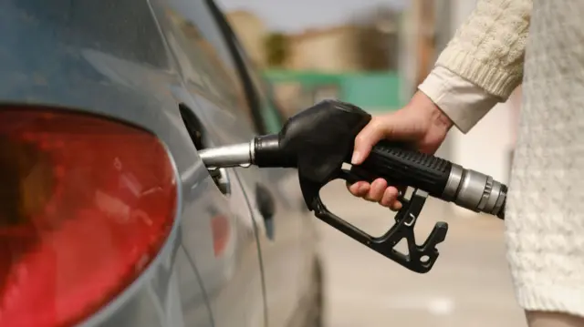 A woman using a fuel pump to fill her car