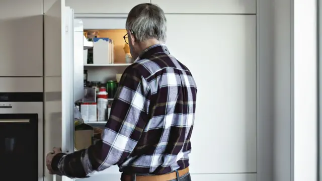 A man holds open a fridge door