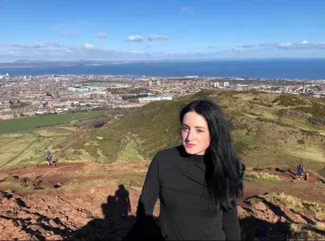 Rebecca Brown poses for a photo on top of a hill