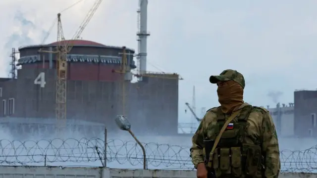 A Russian serviceman stands guard in front of the Zaporizhzhia nuclear power plant