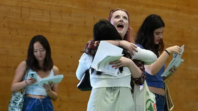 Jubilant students hug after receiving their grades at a school in London