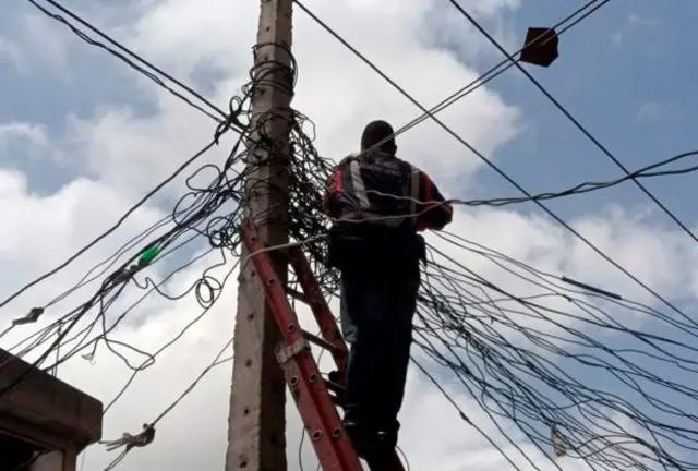 A Nigerian worker repairs a power line