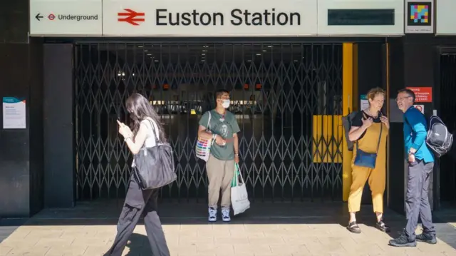 People stand outside the closed entrance to Euston station in London