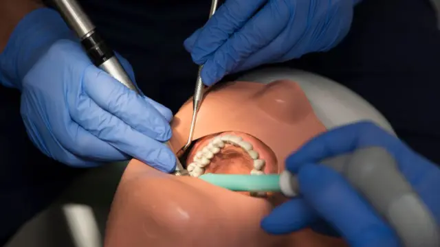 A dental student in training with a training dummy